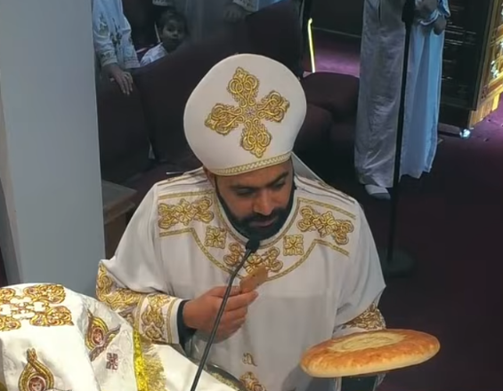 A priest holding the Alleluia Fai Pe Pi hymn book during the liturgy